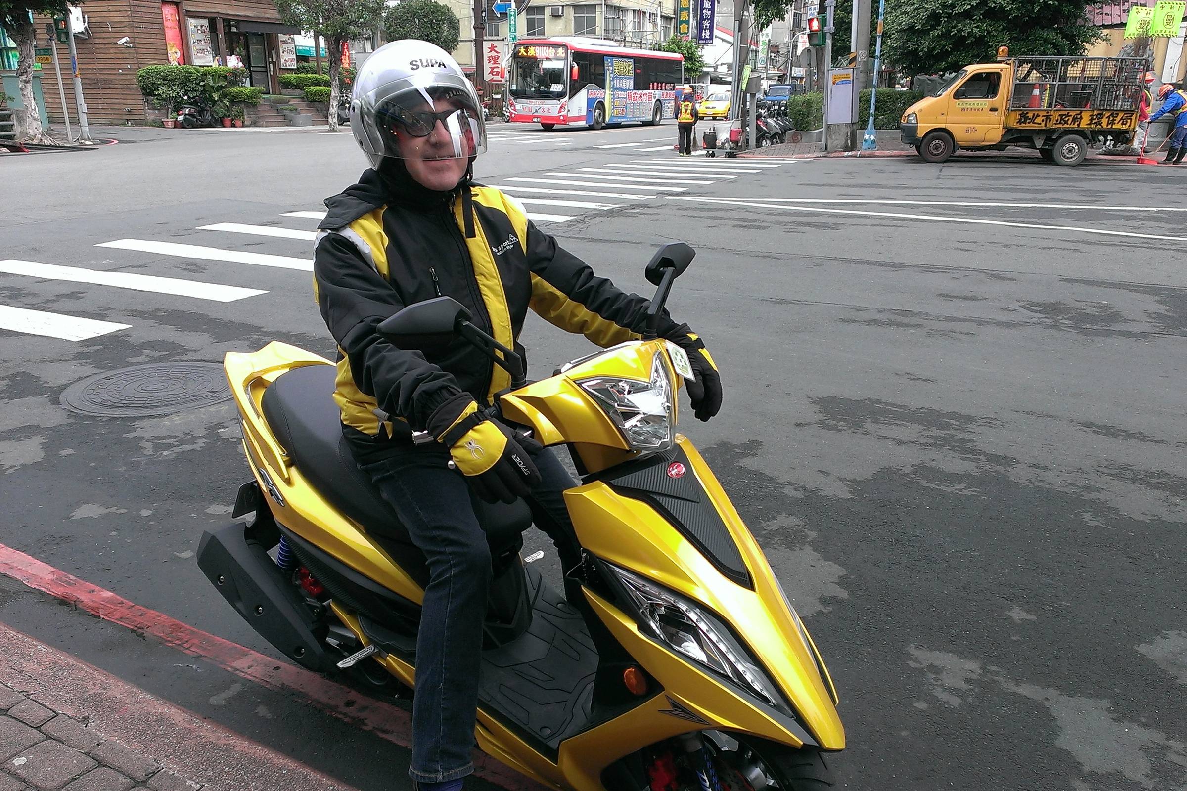 Jacques Botte sur un scooter SYM jaune dans une rue de Taipei, décembre 2015.